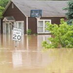 Flooded street with a house covered by flood insurance