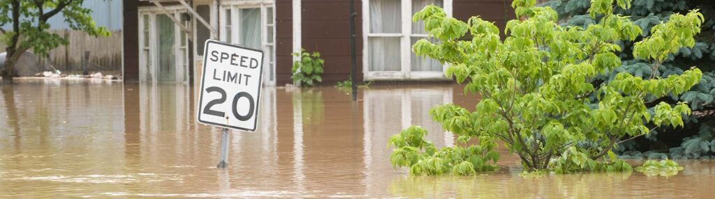 Flooded street with a house with flood insurance