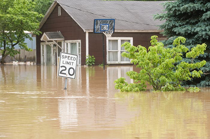 Flooded street with a house covered by flood insurance